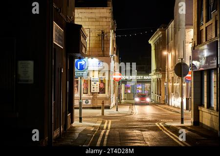 City at night. Solitary red car on deserted street in middle of town centre Stock Photo