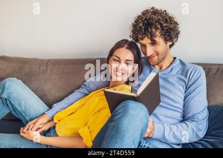 Portrait of young happy couple at home. They are relaxing at sofa. Stock Photo