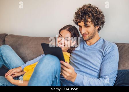 Portrait of young happy couple at home. They are relaxing at sofa. Stock Photo