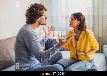 Man and woman are sitting at sofa and arguing. Relationship problems. Stock Photo