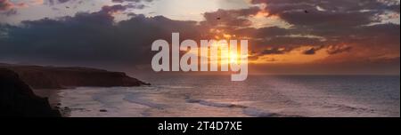 Orange colored sunset with dramatic dark clouds at the beach of La Pared, Fuerteventura Stock Photo