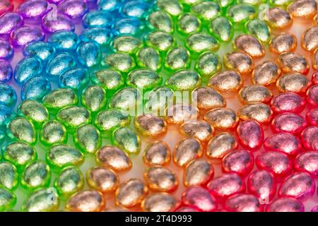 Shiny, metallic, foil-wrapped chocolate eggs arranged in a multi-colored, rainbow composition. Delicious Easter sweets. These delicious treats bring j Stock Photo