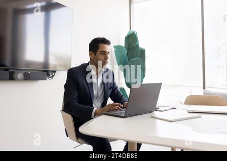 Focused handsome Indian businessman working at laptop Stock Photo