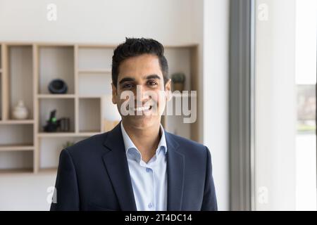 Happy handsome Indian businessman in formal suit looking at camera Stock Photo