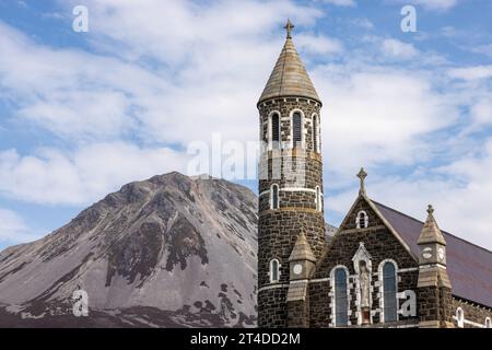 The Sacred Heart Catholic Church in Dunlewey, Ireland, is a landmark with its Hiberno-Romanesque style and round tower, nestled between Mount Errigal Stock Photo