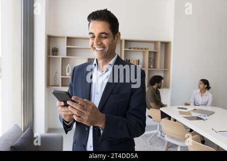 Positive handsome Indian businessman using application on mobile phone Stock Photo