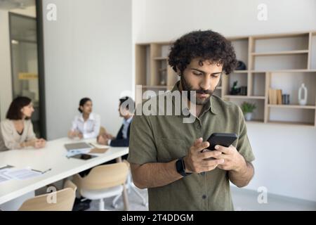 Focused young Arab business professional man typing on mobile phone Stock Photo