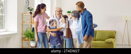 Happy multi-generational family who are happy to see each other hugging while meeting at home. Stock Photo