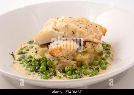 pieces of smoked haddock and pollock in a creamy cheese sauce with fresh peas Stock Photo