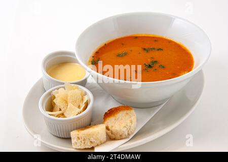 Fresh tomato soup in a bowl with bread, cream and parmesan cheese. Stock Photo