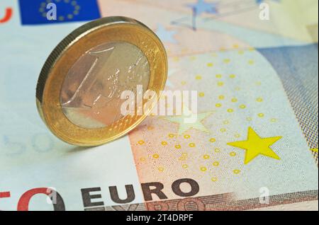 one euro coin standing on banknote Stock Photo