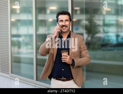 Middle eastern businessman talking on phone while walking by street Stock Photo
