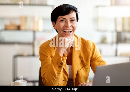 Happy business lady posing at work table with laptop indoor Stock Photo