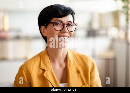 Portrait of happy middle aged woman smiling at camera indoors Stock Photo