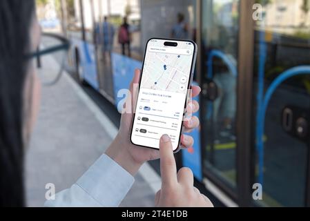 Public transportation app on smartphone in woman hands concept. Bus on station in background Stock Photo