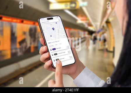 Metro public transport app with map and departures on smart phone in woman hands. Metro underground in background Stock Photo