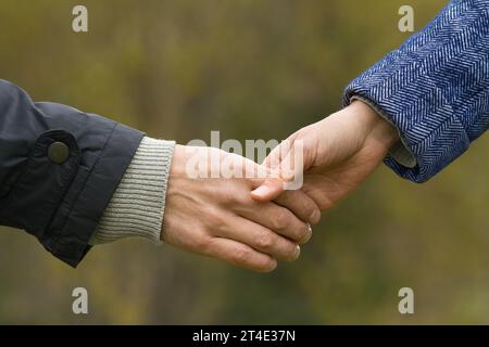 hands of a man and a woman holding hands on blurred background Stock Photo