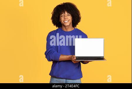 Check This Website. Smiling Black Guy Holding Laptop Computer With Blank Screen Stock Photo