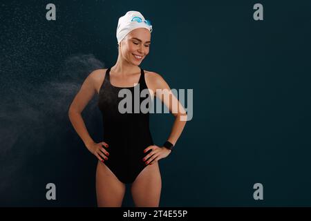 Young smiling woman swimmer in a swimsuit standing with closed eyes Stock Photo
