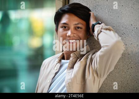 Portrait of happy young asian man standing by city building Stock Photo