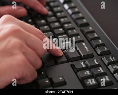 A man typing on a black computer keyboard. Close up. Stock Photo