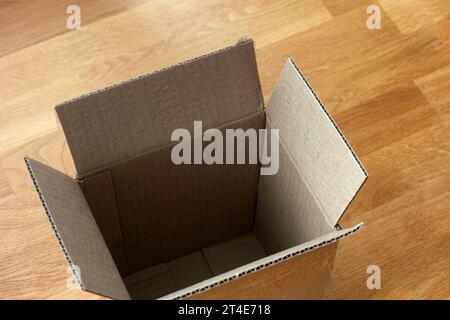 An empty cardboard box on a wooden floor. Close up. Stock Photo