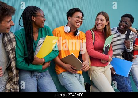Happy group of multiracial students gathering having fun, talking and laughing after school. Stock Photo
