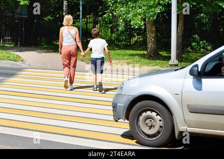 Mother and child walk on pedestrian crossing Stock Photo