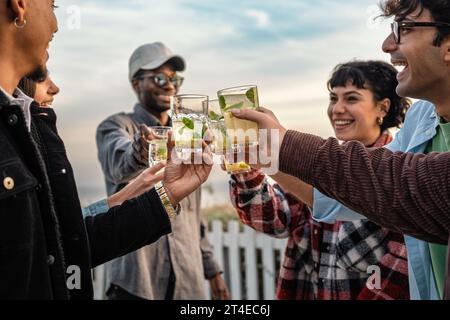 Cheerful friends with summer drinks - Joyful group of friends raising glasses filled with refreshing drinks, toasting to a good time outdoors with a c Stock Photo