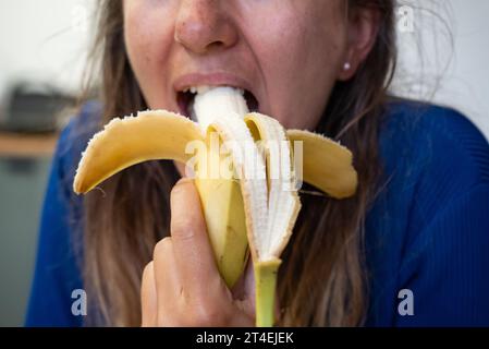 Woman eats food. Woman eats  banana. Close shot of girl eating  bananas. Face while eating banana Stock Photo