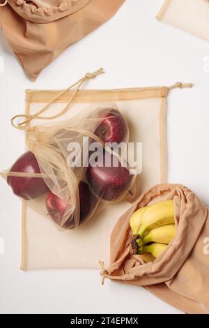Red apples and bananas in reusable bags. Zero waste concept. Stock Photo