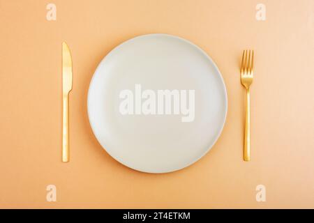Empty plate with fork and knife on orange background. Diet concept. Top view, flat lay. Stock Photo