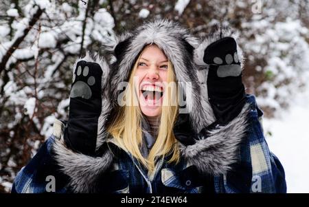 Winter holidays. Fashion girl in wintertime. Happy woman in warm coat, fur hat and mittens. Cold winter weather. Christmas girl in warm clothes in Stock Photo