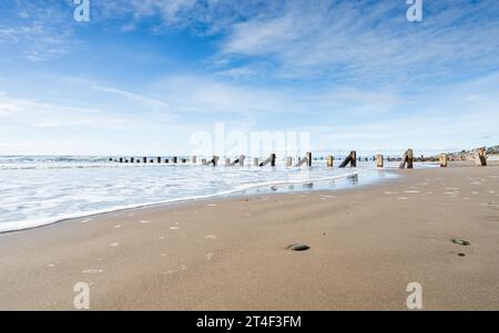 A low angle image of the wooden groynes on beach at Barmouth on the Welsh coastline. Stock Photo