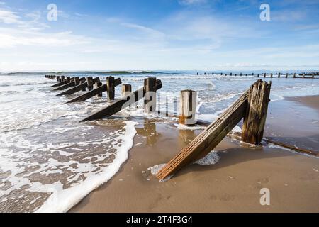 Waves break around the wooden groynes on the beach at Barmouth on the Welsh coast. Stock Photo