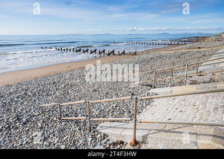 Railings and steps lead down to the pebbles and sand on Barmouth beach on the Welsh coast. Stock Photo