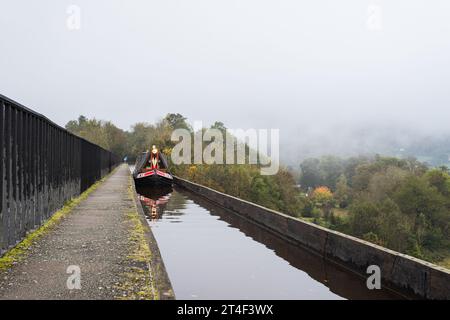 A colourful narrow boat reflects in the calm water on the Llangollen Canal as ut stretches over the Pontcysyllte Aqueduct. Stock Photo