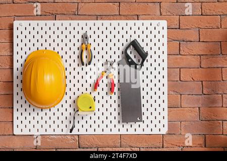 Pegboard with builder's tools on brick wall in workshop Stock Photo