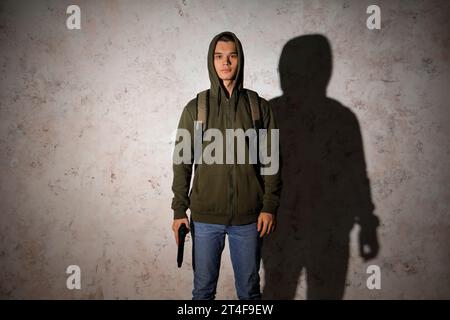 Male student with gun near grunge wall Stock Photo