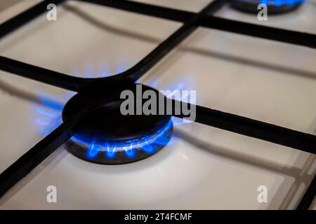 The gas burns in the burner of a kitchen stove. Stock Photo