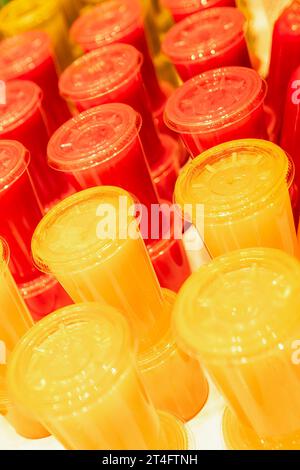 Colorful plastic glasses with juice in a row, closeup of photo Stock Photo