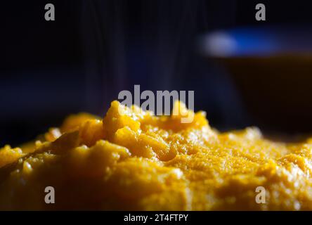 Polenta with omelette with steam on black background. Selective focus. Stock Photo
