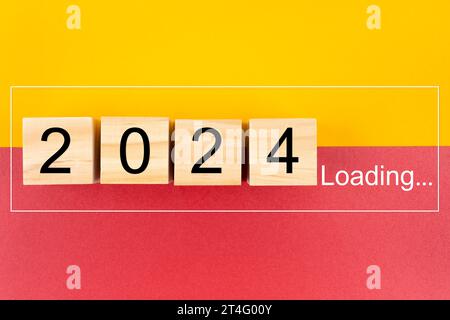 New Year 2024 Loading with wood block on yellow and red background. Stock Photo