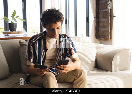 Happy biracial man using smartphone with credit card at home Stock Photo