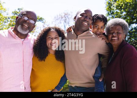 Portrait of happy african american family embracing in sunny backyard, copy space Stock Photo