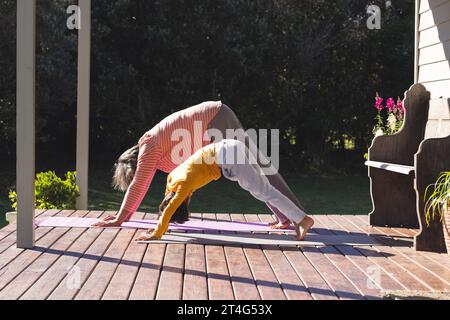 Happy biracial grandmother and grandson doing yoga and stretching in garden Stock Photo