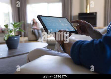 Midsection of senior caucasian man sitting on sofa using tablet with smart home interface Stock Photo