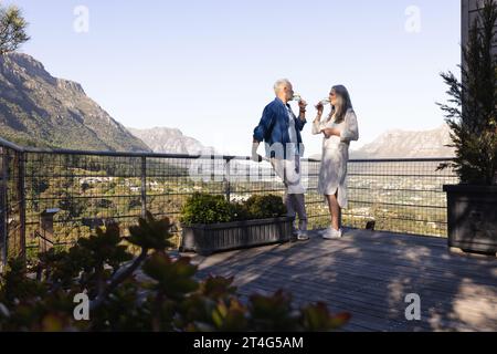 Happy senior caucasian couple drinking wine on balcony, copy space Stock Photo