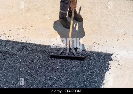 On the sidewalk, road workers leveling freshly laid hot asphalt, aerial view Stock Photo