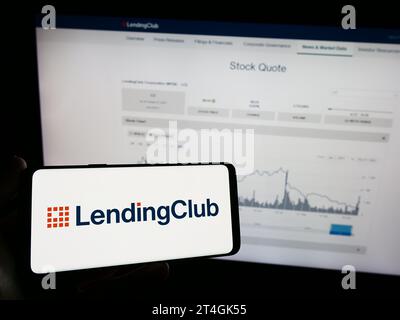 Person holding mobile phone with logo of American financial services company LendingClub Corporation in front of web page. Focus on phone display. Stock Photo